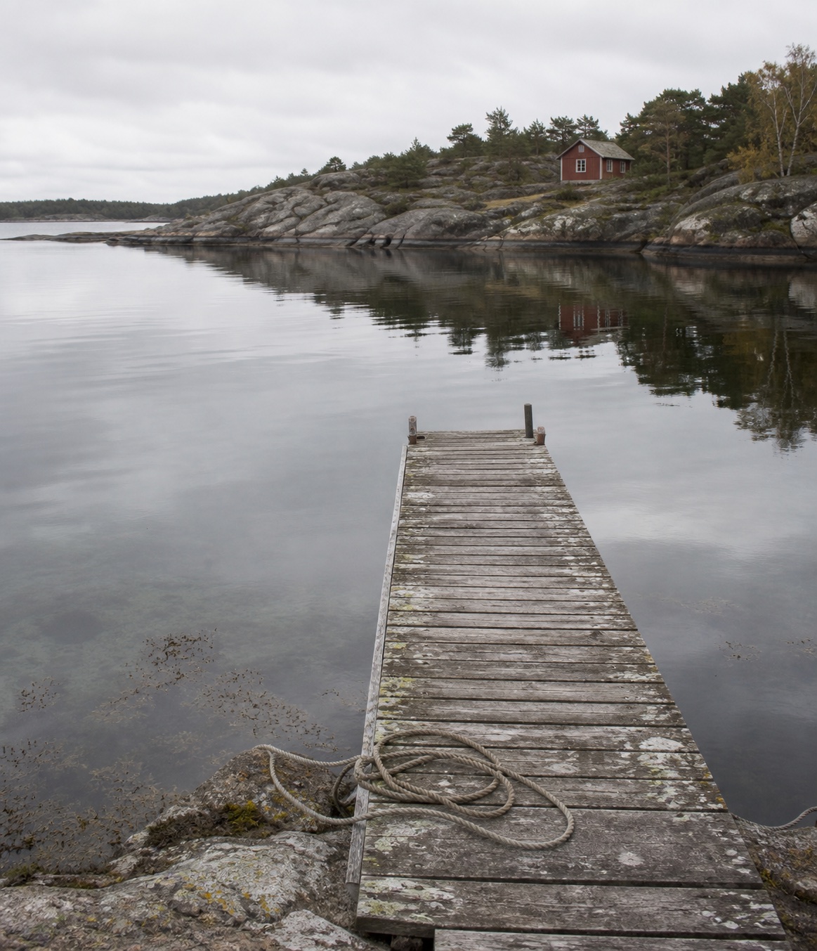 En værslitt trebrygge ved et stille sørlandsskjær, brukt i et merket eksempelminne